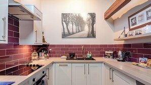 Een moderne keuken met witte kasten, een backsplash van rode tegels en een houten plafond.