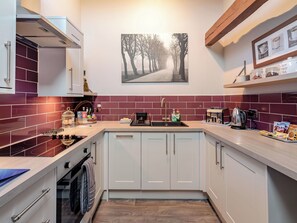 A modern kitchen with white cabinets, a red-tiled backsplash, and a wooden ceiling. - 1 bedroom accommodation in Bilbrough, near York (Bilbrough, near York)