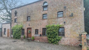 A brick building with a gravel courtyard, multiple windows, and a door with a wreath. - Apartment Two - UK41162 (Bilbrough, near York)
