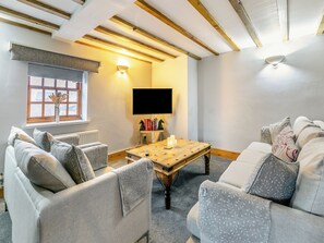 Una sala de estar acogedora con una mesa de centro de madera, un televisor de pantalla plana y asientos cómodos.