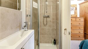 A bathroom with a glass-enclosed shower, a white bathtub, and a wooden dresser. - Apartment Two - UK41162 (Bilbrough, near York)