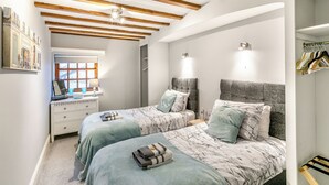 A bedroom with two beds, wooden beams on the ceiling, a window, a desk with a lamp, and a wardrobe. - Apartment Two - UK41162 (Bilbrough, near York)