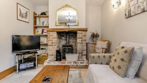 Una sala de estar con chimenea, televisor, sofá y mesa de centro.