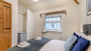 Un dormitorio con cama, armario, radiador y ventana con cortinas.