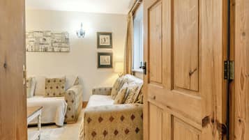 A cozy room with two patterned sofas, a wooden wardrobe, and a wall-mounted artwork.
