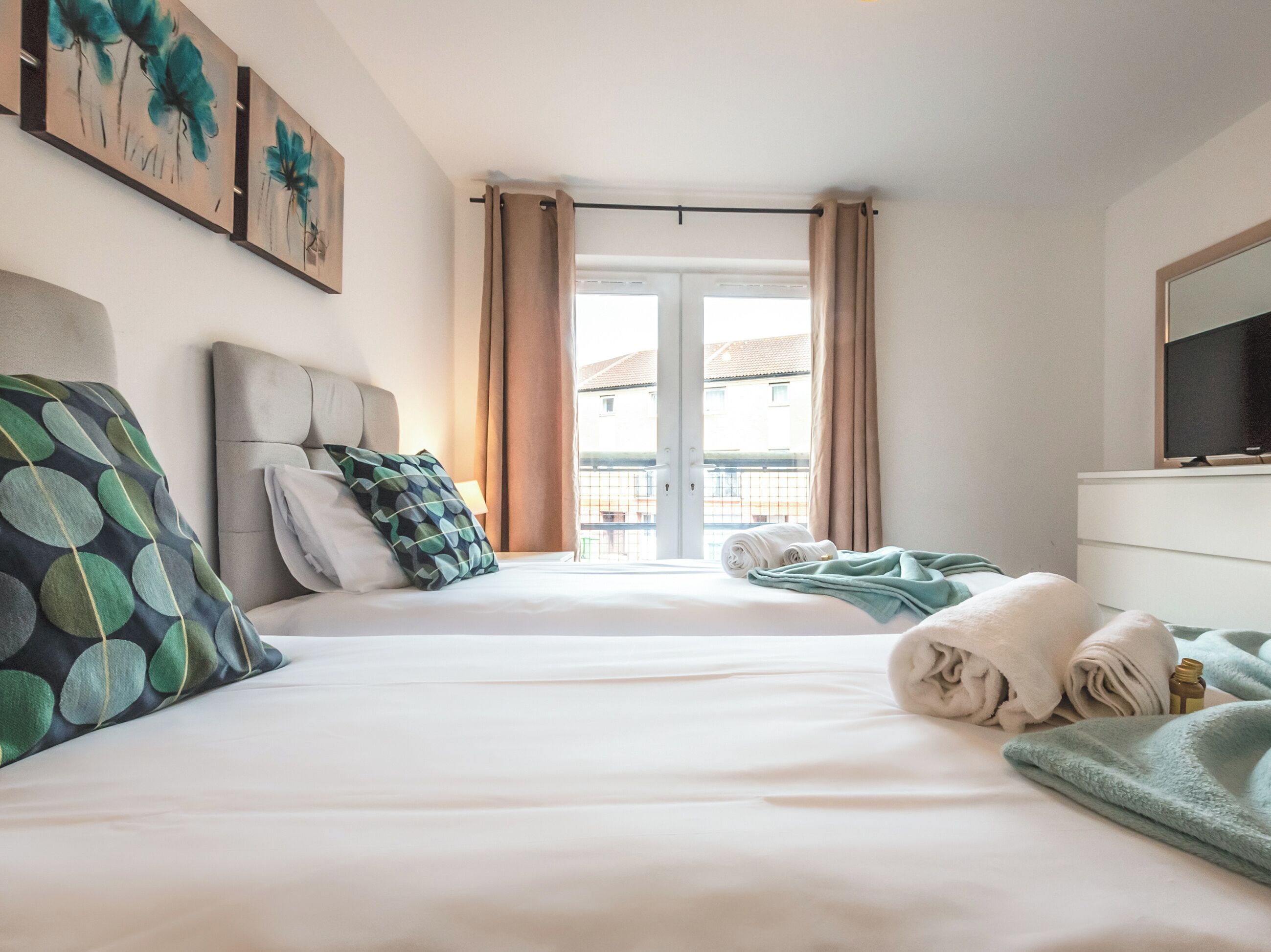 A hotel room with a bed, a television, and a view of the outside.