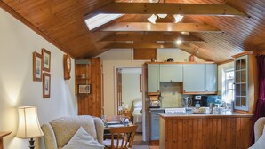 A cozy living room with a fireplace, a dining area, and a kitchen with wooden cabinets. - 2 bedroom accommodation in Winfrith Newburgh (Winfrith Newburgh)