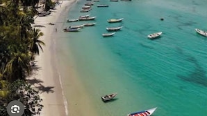 Un paisaje urbano costero con playa, barcos y edificios.