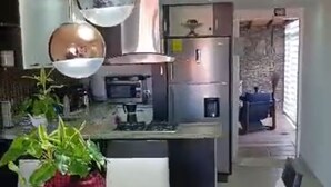 A modern kitchen with stainless steel appliances, pendant lighting, and a dining area with a table and chairs.