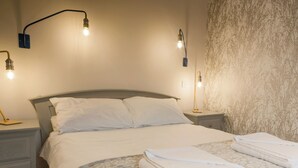A neatly made bed with white linens and a patterned blanket, two bedside lamps, and a wall with a textured design. - Peveril Cottage - E4642 (Darwin Lake, near Matlock)