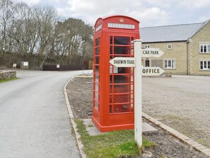 Eine rote Telefonzelle mit Hinweisschildern für 'Darwin Trail' und 'Car Park Office'.