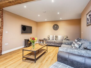 A living room with a sofa, a coffee table, a fireplace, and a clock on the wall. - Oyster Catcher - UK32200 (Skegness)