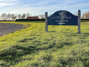 Señal de bienvenida de Lincolnshire Coastal Cottages con una flecha indicadora.