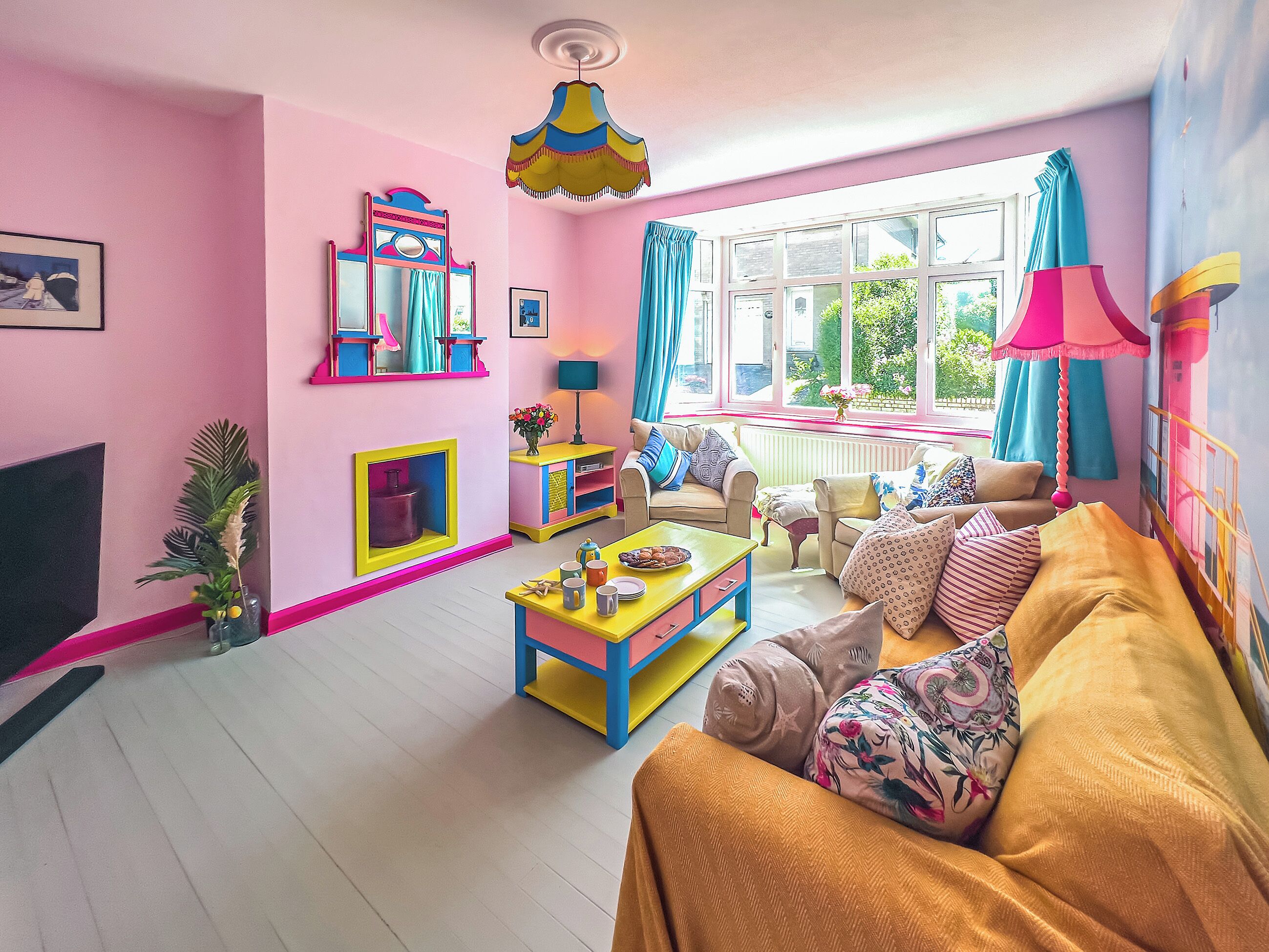 Een vrolijk ingerichte woonkamer met een bank, een salontafel en een televisie.