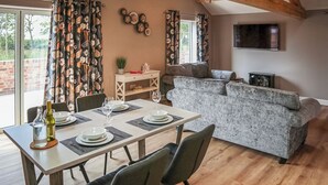 Et spiseområde med et bord dækket til fire personer, en sofa og et fjernsyn ophængt på væggen.