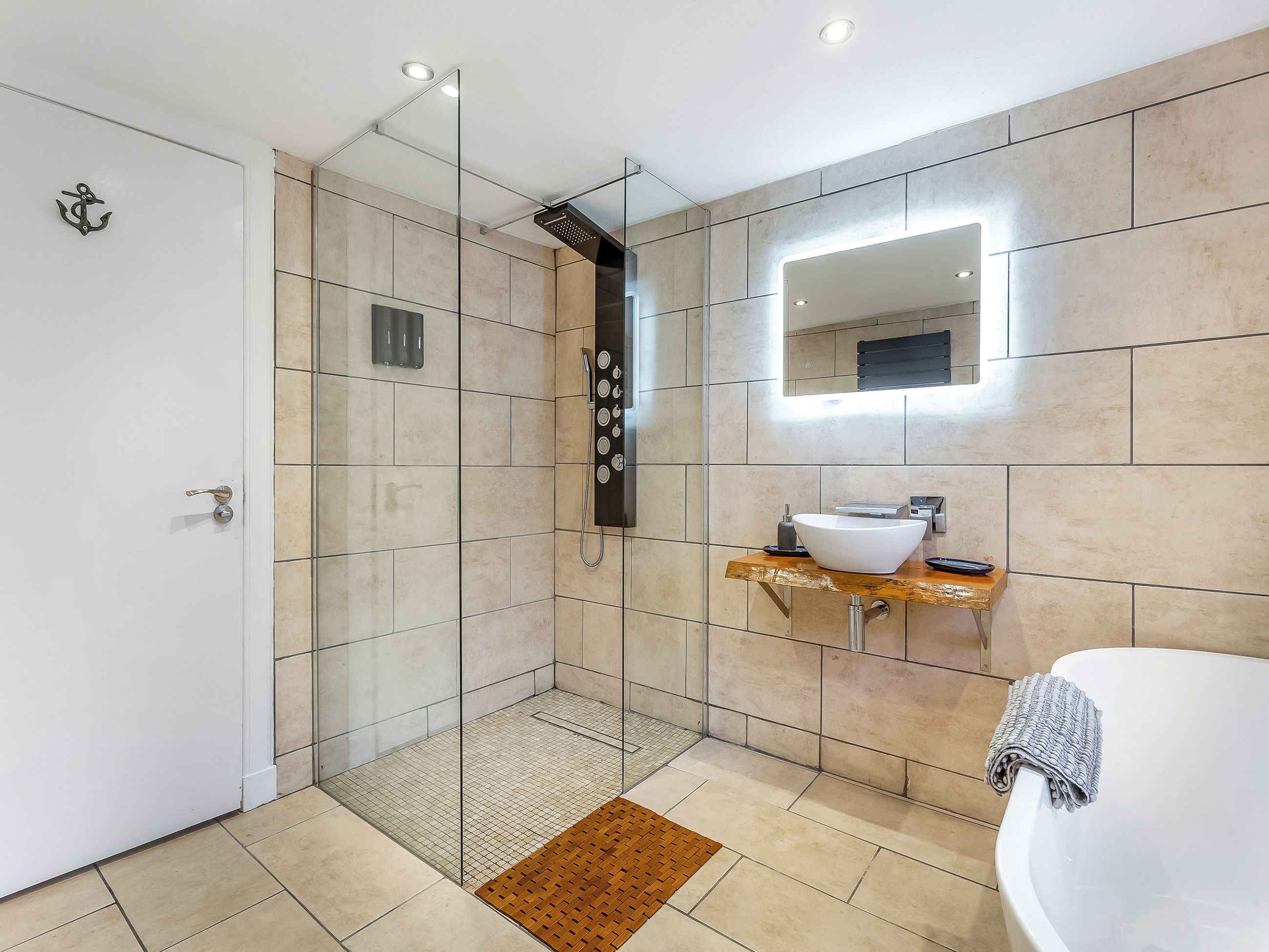 Un baño moderno con cabina de ducha de vidrio, un lavamanos blanco y un espejo.