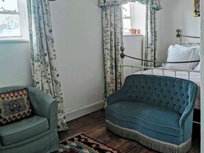 A room with a blue upholstered sofa, a patterned armchair, and a bed with a white headboard. - UK41465 - The Coach House (Cholderton, near Salisbury)