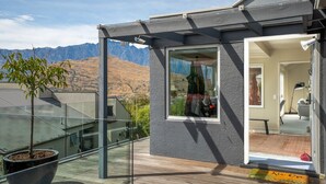 Een modern huis met een balkon, een groot raam en uitzicht op bergen.