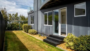 Een modern huis met twee verdiepingen, grote ramen, een verzorgd gazon en een kleine tuin.