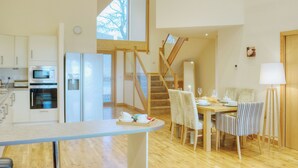 Eine moderne Küche mit eingebauten Geräten, ein Essbereich mit gestreiften Stühlen und eine Treppe, die in ein Obergeschoss führt.