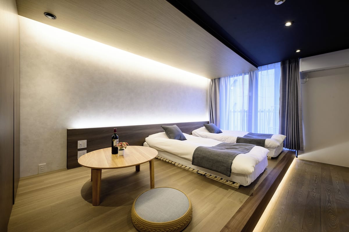 A modern hotel room with a bed, bedside tables, a round table, and a small round seating area.