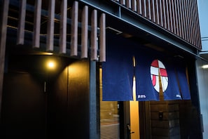 Une façade d’immeuble avec un auvent bleu sur lequel figure un logo et du texte en japonais.