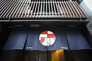 Ein Gebäude mit moderner Fassade, das ein großes Logo und eine Beschilderung für das Aka Hotel zeigt.