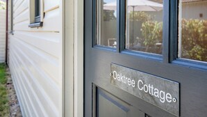 Uma casa com uma placa que diz 'Oaktree Cottage'.