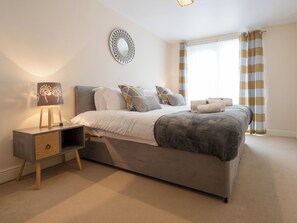 A bedroom with a bed, bedside table, lamp, and curtains. - Beautiful apartment in central Ashford with its own private balcony. (Ashford)