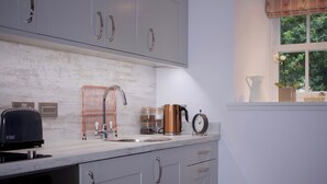 A kitchen with grey cabinets, a stainless steel sink, a coffee maker, and a clock.