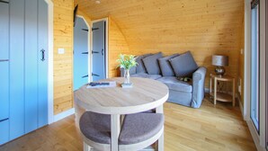 Un intérieur en bois avec une table ronde, un canapé gris et une lampe.