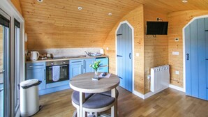 Un intérieur en bois comprenant une cuisine, un coin repas et un téléviseur fixé au mur.