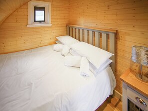 A wooden-paneled room with a bed, pillows, and a nightstand.