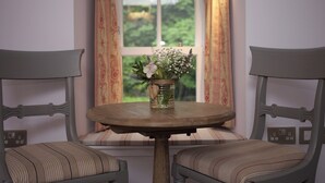 A room with a round wooden table and two upholstered chairs with striped cushions. A vase with flowers is placed on the table. - 1 bedroom accommodation in Oldmeldrum, near Inverurie (Oldmeldrum, near Inverurie)