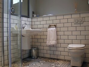 A bathroom with a glass shower enclosure, a white sink with a mirror, a white toilet, and a patterned floor. - 1 bedroom accommodation in Oldmeldrum, near Inverurie (Oldmeldrum, near Inverurie)