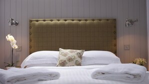 A neatly made bed with white linens and a decorative pillow, a wall-mounted light fixture, and a potted orchid plant. - 1 bedroom accommodation in Oldmeldrum, near Inverurie (Oldmeldrum, near Inverurie)