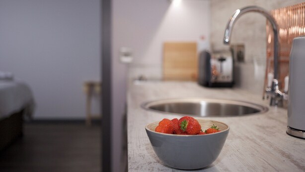 A modern kitchen with a bowl of strawberries on the counter, a sink, and a coffee machine. - 1 bedroom accommodation in Oldmeldrum, near Inverurie (Oldmeldrum, near Inverurie)