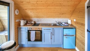 A compact kitchen with wooden ceiling, a sink, a stove, and a refrigerator. - A good sized, dog friendly pod with silent surroundings. (Archaracle)
