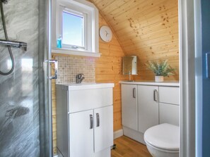 A compact bathroom with a shower, a sink, a toilet, and a mirror. - A good sized, dog friendly pod with silent surroundings. (Archaracle)