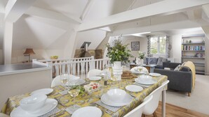 A dining area with a table set for six, a white railing, and a bookshelf in the background. - 3 bedroom accommodation in Bovey Tracey (Bovey Tracey)