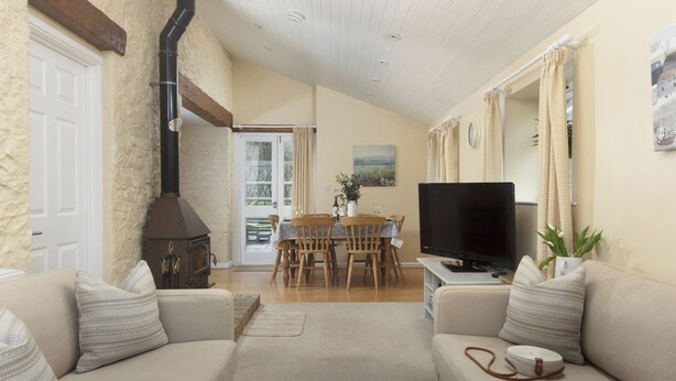 A living room with a fireplace, a television, a dining table with chairs, and a sofa. - 3 bedroom accommodation in Bovey Tracey (Bovey Tracey)