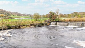 Een landelijk landschap met een waterval, stenen muren en een omheind veld.