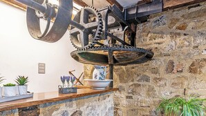 Una cucina rustica con pareti in pietra a vista, un bancone in legno e un ingranaggio meccanico di grandi dimensioni.