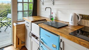 Cozinha compacta com bancada de madeira, pia, chaleira e geladeira azul.