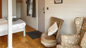 Quarto com cama, uma cadeira e piso de madeira.