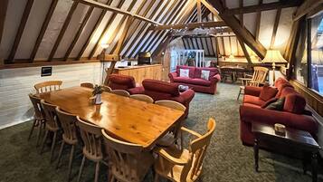 Ein gemütliches Dachzimmer mit Holztisch, roten Sofas und einer Küchenzeile.