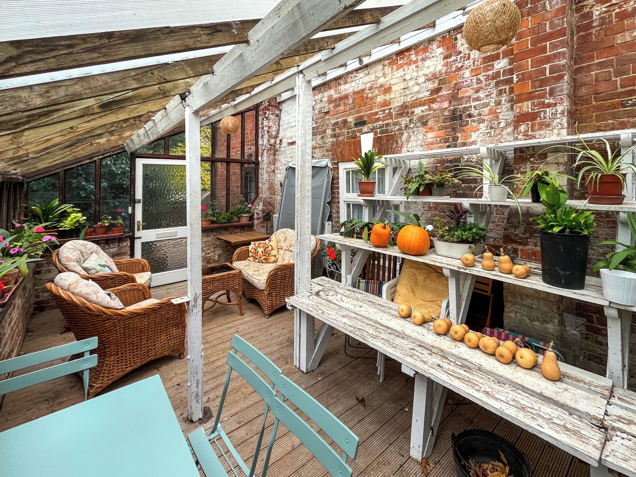 A rustic patio with wicker furniture, a wooden table, and a brick wall.