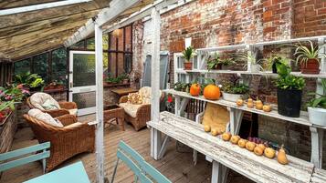 A rustic patio with wicker furniture, a wooden table, and a brick wall.