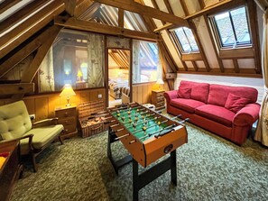 Een gezellige kamer met een tafelvoetbaltafel, een rode bank en een houten plafond.