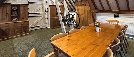 A dining area with a wooden table and chairs, a kitchen with a stove and cabinets, and a loft space with a bicycle wheel.